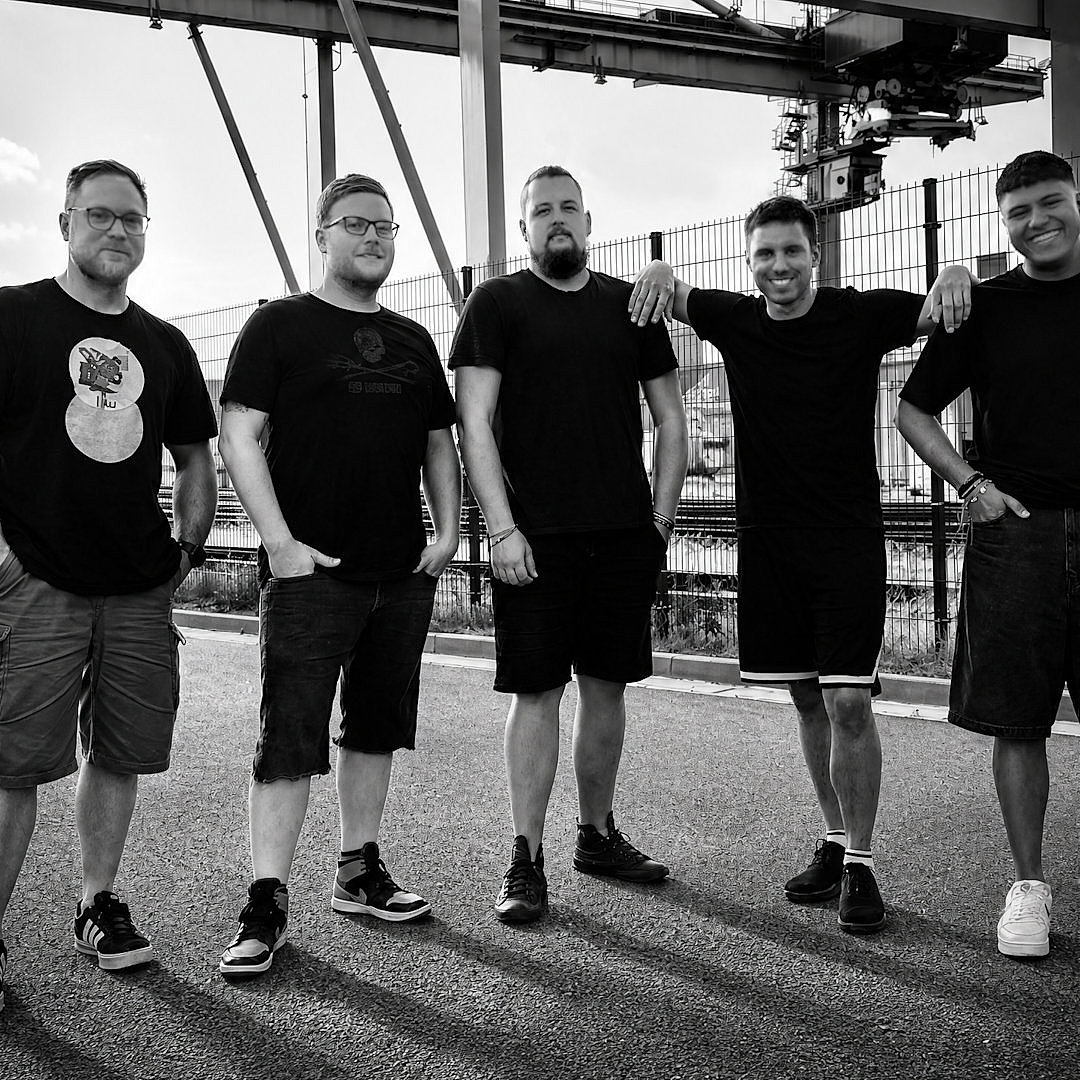 Die Mitglieder der Band in schwarz und weiß stehen vor Stahlträgern